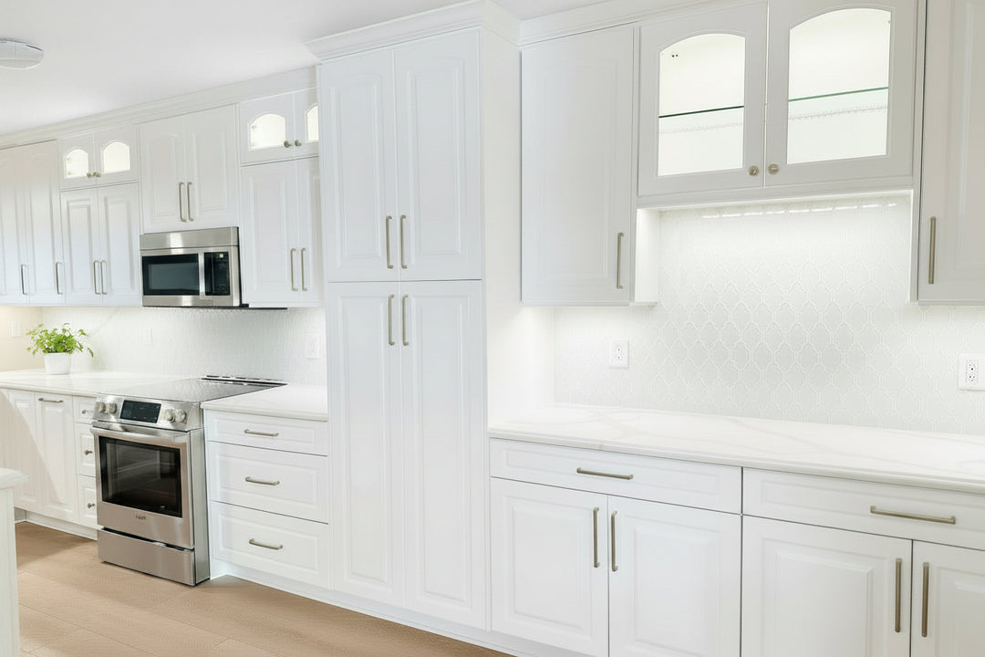 Modern kitchen with white cabinets, stainless steel appliances, and wooden flooring.