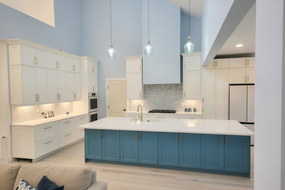 Modern kitchen with blue and white cabinets, island, and pendant lights.